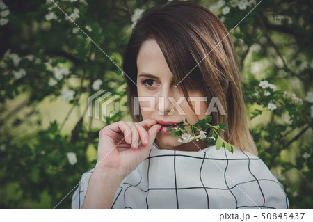young woman in a checkered dressstay near a flowering tree young woman in a checkered dressstay near a flowering tree 50845437