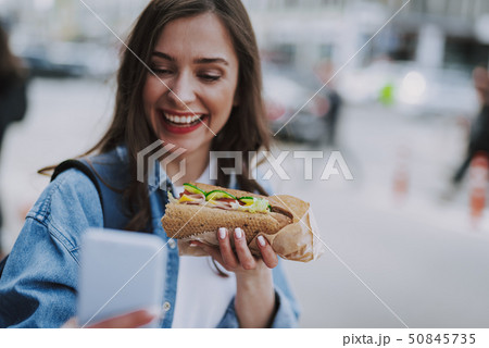 Joyful female making selfie with hot dog Joyful female making selfie with hot dog 50845735