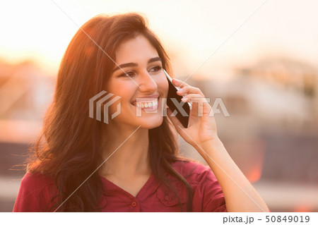 Happy student talking on smartphone, walking at sunset Happy student talking on smartphone, walking at sunset 50849019