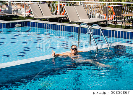 Young beautiful Woman sunbathing in swimming pool at luxurious looking on sunshade parasol in Egypt 50856867