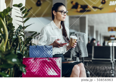 Young businesswoman is relaxing with coffee and phone in airport 50856963