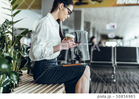 Businesswoman with coffee is using smartphone before plane 50856965