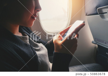 Tourist Asian woman sitting near airplane window Tourist Asian woman sitting near airplane window 50863678
