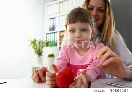 Little baby girl visiting doctor holding in hands red toy heart Little baby girl visiting doctor holding in hands red toy heart 50865162