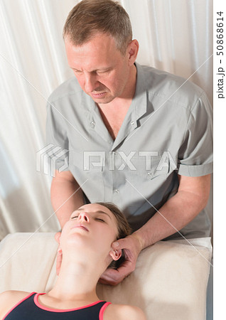 Male manual visceral therapist masseur treats a young female patient. Head and ear massage Male manual visceral therapist masseur treats a young female patient. Head and ear massage 50868614