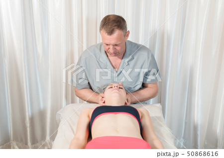 Male manual visceral therapist masseur treats a young female patient. Head and ear massage Male manual visceral therapist masseur treats a young female patient. Head and ear massage 50868616