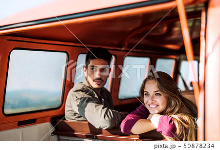 A young couple on a roadtrip through countryside, sitting in minivan. 50878234