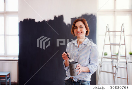A portrait of young woman painting wall black. A startup of small business. A portrait of young woman painting wall black. A startup of small business. 50880763