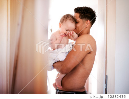 Father and small toddler son wrapped in towel in a bathroom indoors at home. Father and small toddler son wrapped in towel in a bathroom indoors at home. 50882436
