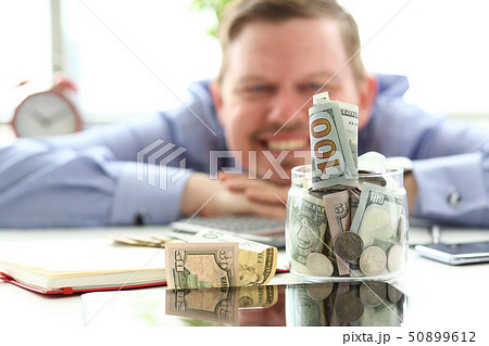 Man looking at jar full of money thinking about his opportunities 50899612