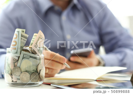 Rich jar full or US banknotes and coins with businessman arms in background counting expenses with 50899888