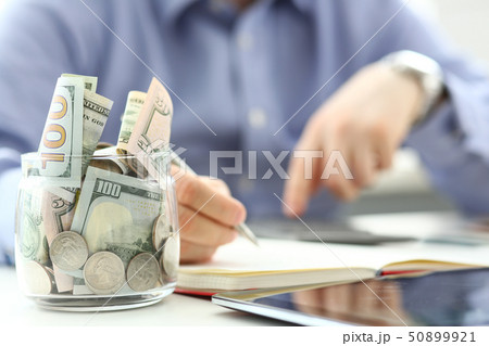 Rich jar full or US banknotes and coins with businessman arms in background counting expenses with Rich jar full or US banknotes and coins with businessman arms in background counting expenses with 50899921