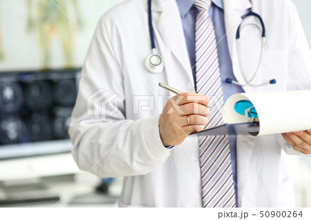 Male doctor checking medical procedure results in document clipped to pad 50900264