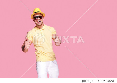 Confident stylish guy showing thumb up at camera Confident stylish guy showing thumb up at camera 50953028