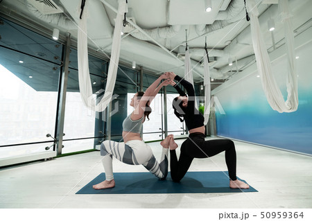 Dark-haired sisters stretching their backs while doing yoga together 50959364