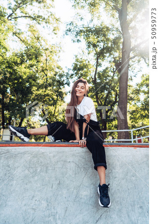 Beautiful young hipster girl sitting on the edge of a ramp 50959773