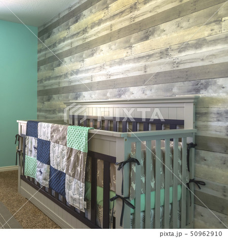 Wooden crib draped with quilt inside a nursery Wooden crib draped with quilt inside a nursery 50962910