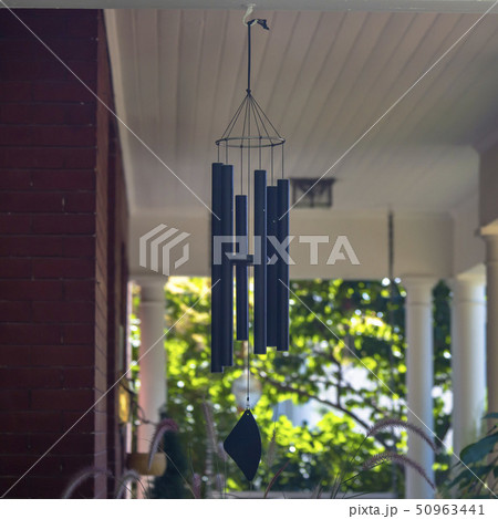 Wind chime on a red brick house with white pillars 50963441