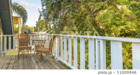 Wicker furniture on balcony overlooking lush trees 51000846