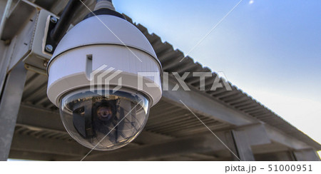 White dome security camera overhanging on a roof 51000951