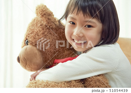椅子に腰掛け大きな熊と遊ぶ女の子 椅子に腰掛け大きな熊と遊ぶ女の子 51054439
