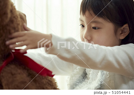 椅子に腰掛け大きな熊と遊ぶ女の子 51054441