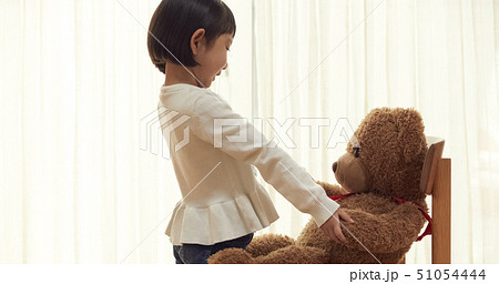 大きな熊を椅子に座らせ遊ぶ女の子 51054444
