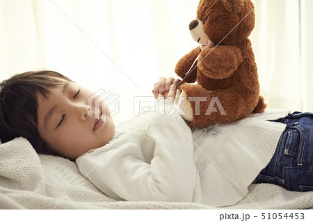 ベッドで小さなクマと寝る女の子 51054453