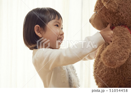 大きなクマを抱き上げる女の子の写真素材