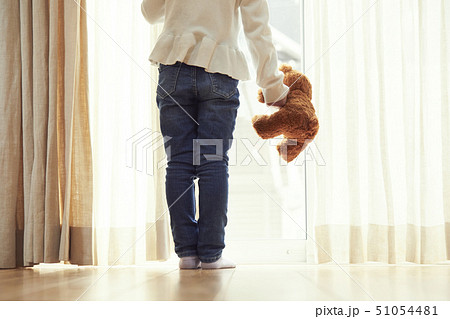 小さなクマを持ち窓際に立つ女の子 小さなクマを持ち窓際に立つ女の子 51054481