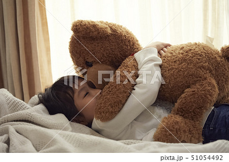 ベッドで大きなクマと寝る女の子 ベッドで大きなクマと寝る女の子 51054492