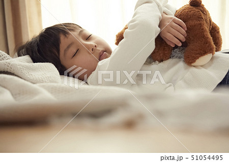 ベッドで小さなクマと寝る女の子 51054495