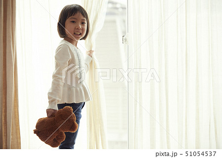 小さなクマを持ち窓際に立つ女の子 小さなクマを持ち窓際に立つ女の子 51054537