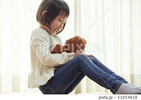 床に座り小さなクマと遊ぶ女の子 51054616