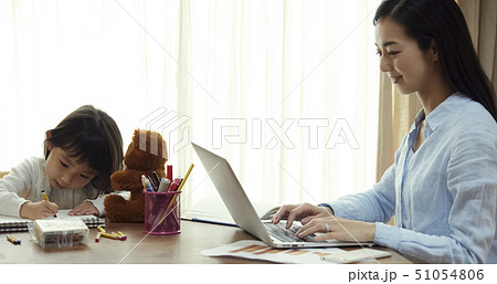 リビングで仕事する母の斜向かいでお絵かきをする娘 51054806