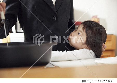 キッチンで夕飯の支度をする母としがみつく娘 51054831