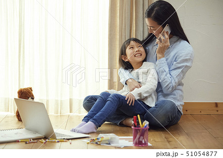床の上でお母さんの膝に抱っこされる娘 51054877