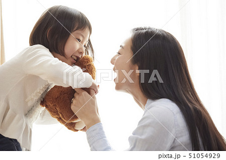 リビングの床で小さなクマと遊ぶ母娘 リビングの床で小さなクマと遊ぶ母娘 51054929