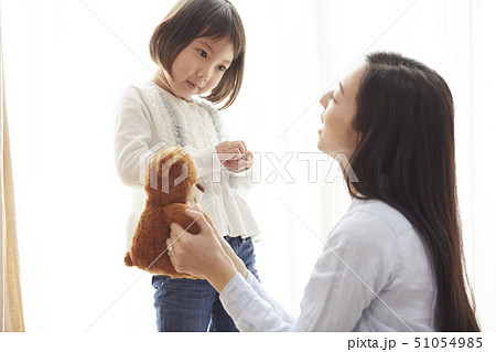 リビングの床で小さなクマと遊ぶ母娘 51054985