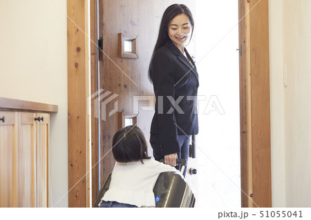 玄関で出張に出掛ける母のスーツケースにしがみつく娘 51055041