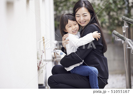 家の外でただいまの抱擁をする母娘 51055167