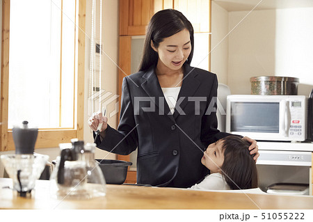 キッチンで夕飯の支度をする母としがみつく娘 51055222