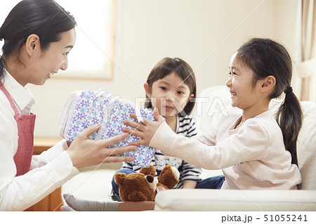 お誕生日にお母さんと妹からプレゼントをもらう女の子の写真素材
