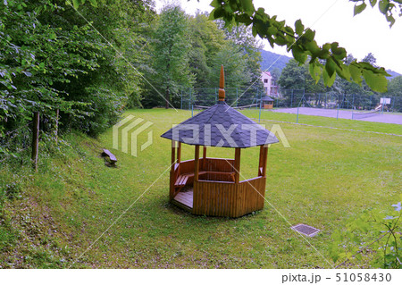 Small wooden gazebo on a green lawn with a tennis Small wooden gazebo on a green lawn with a tennis 51058430