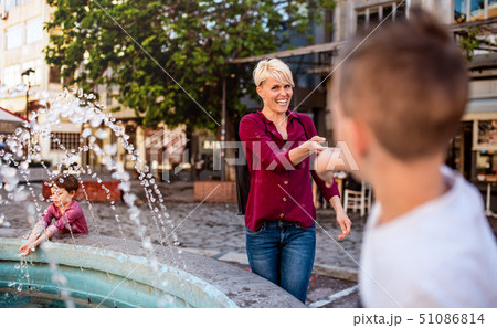 Young mother with two small children having fun outdoors in town. Young mother with two small children having fun outdoors in town. 51086814