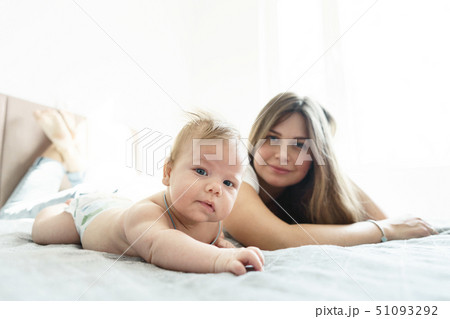 Mother with her newborn son lay on the bed in the rays of sunlight Mother with her newborn son lay on the bed in the rays of sunlight 51093292