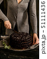Woman cuts chocolate cake close. Dark tones 51111436