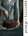 Woman cuts chocolate cake close. Dark tones 51111468