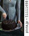Woman cuts chocolate cake close. Dark tones 51111498