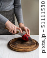 Woman cuts red apple on board close 51111530